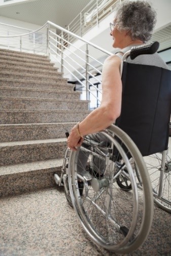 Osoba u invalidskim kolicima stoji ispred stepenica
